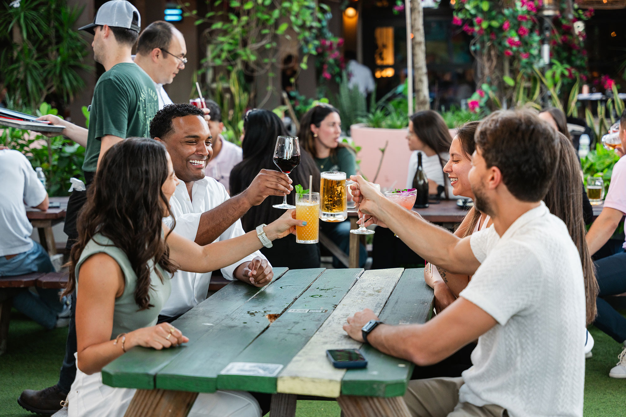 Friends toasting drinks at an outdoor table in Downtown Doral